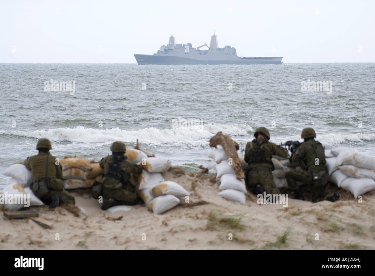 Soldados polacos en la playa y en el reverso un estadounidense San Antonio de transporte anfibio de la clase base USS Arlington LPD-24 durante la 45ª edición de E Foto de stock