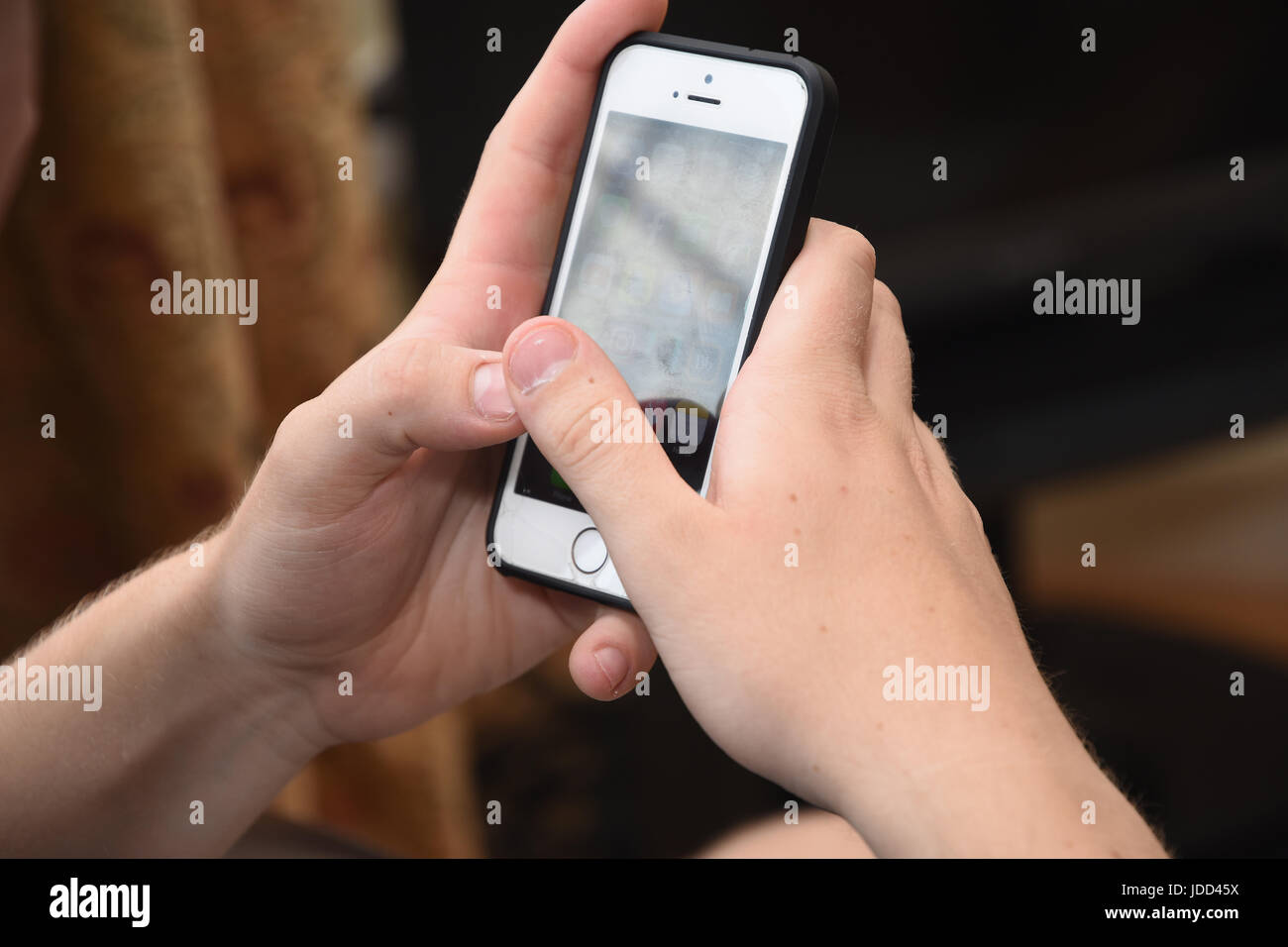 Adolescente de 19 años con un iPhone de Apple se teléfono móvil para leer y enviar mensajes de texto Foto de stock