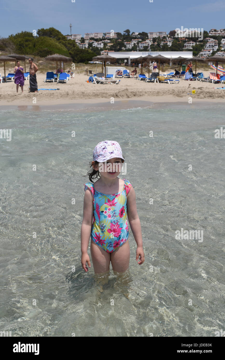 Chica de pie en el mar en una playa de arena Foto de stock