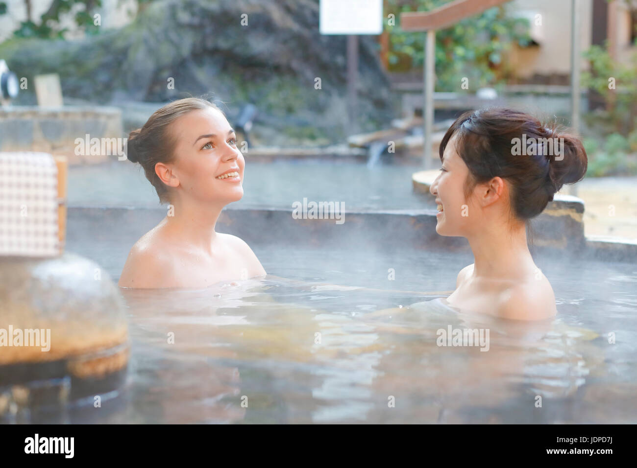 Mujer caucásica con amigo japonés tradicional bañarse en aguas termales, Tokio, Japón Foto de stock