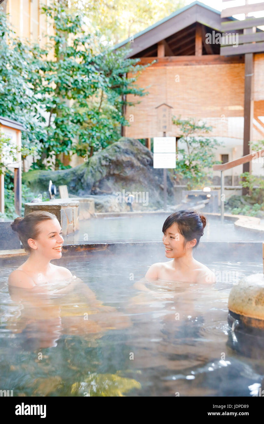 Mujer caucásica con amigo japonés tradicional bañarse en aguas termales, Tokio, Japón Foto de stock