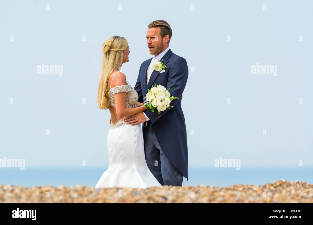 La novia y el novio en una playa con fotos tomadas durante el día de su boda. Pareja casada. Casarse. Día del matrimonio. Foto de stock