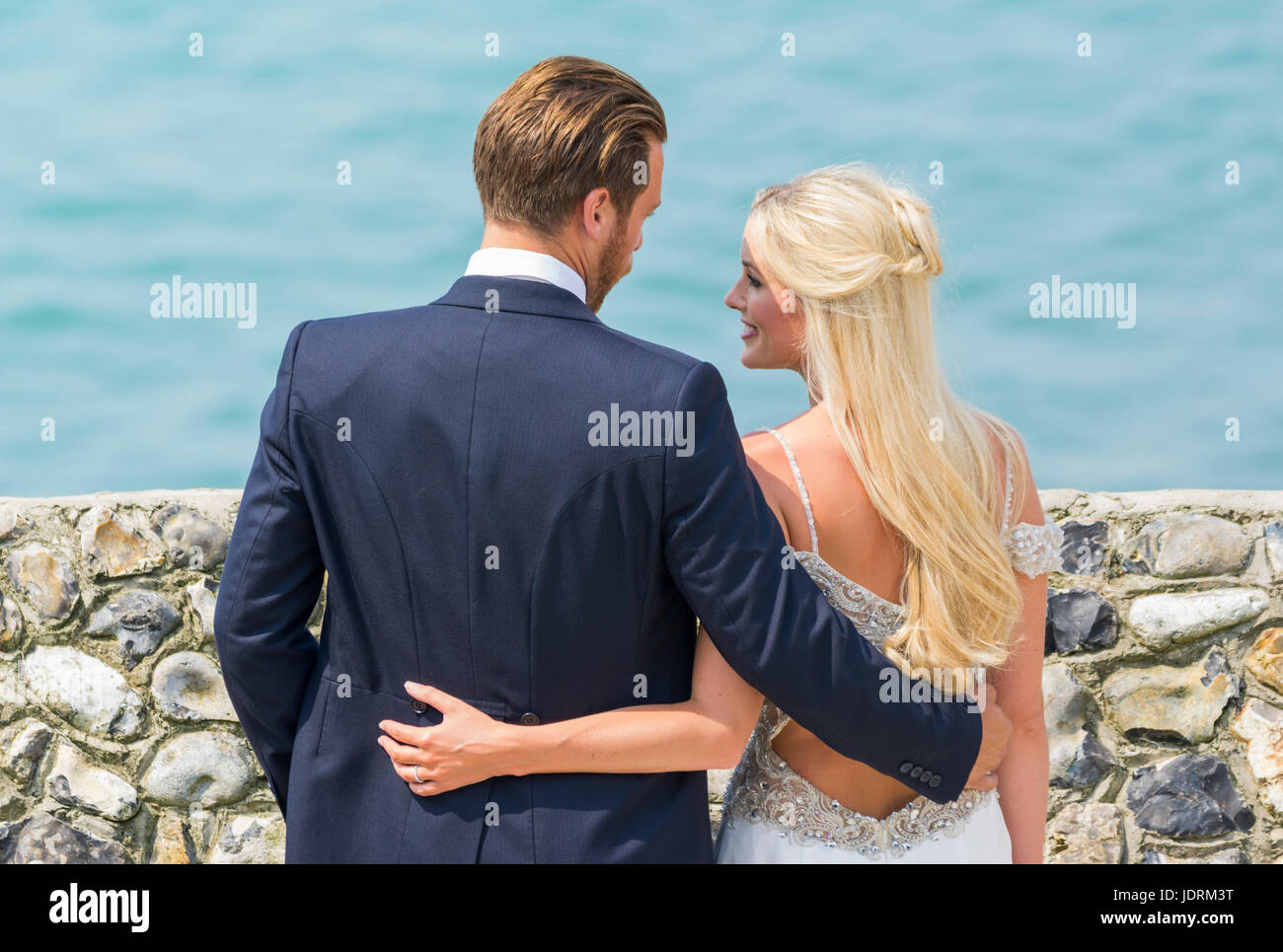 La novia y el novio en una playa con fotos tomadas durante el día de su boda. Pareja casada. Casarse. Día del matrimonio. Foto de stock