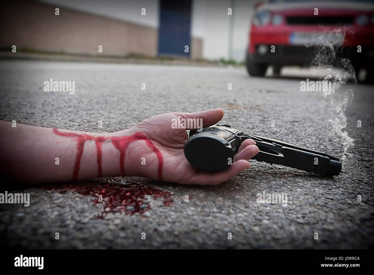 El hombre con la pistola en la mano ensangrentada yace muerto en el asfalto de la víctima de asesinato Foto de stock