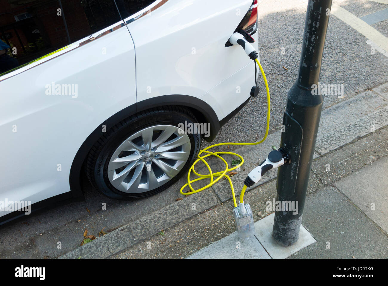 Una conversión de cargador eléctrico de coche por Ubitricity: Cable inteligente en una lámpara de calle que ahora se puede utilizar para cargar un vehículo con EV desde el poste de la lámpara (en este caso un Tesla.) Twickenham Reino Unido Foto de stock