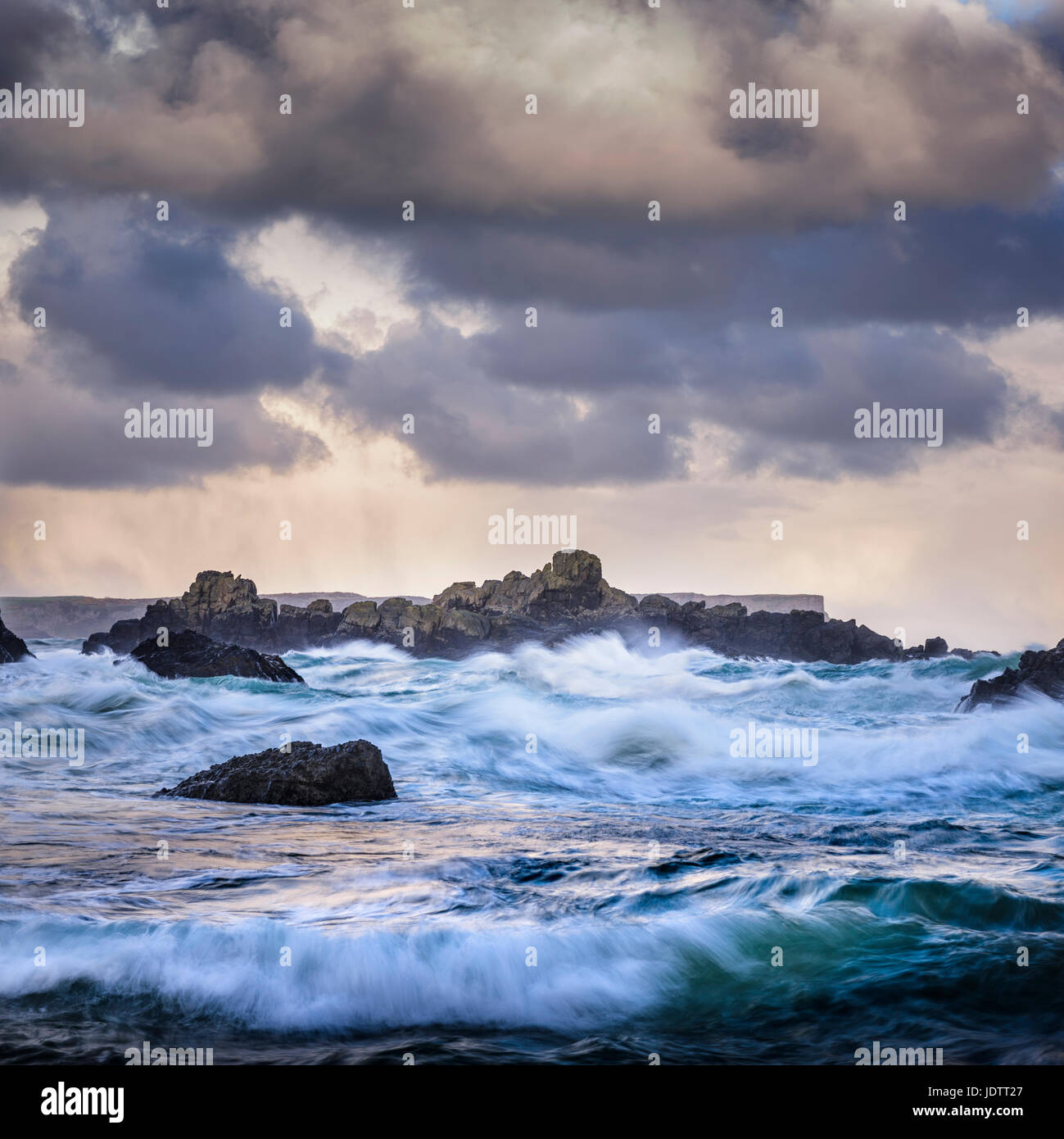 Ominosa tormenta el cielo y el mar, con las olas rompiendo en la orilla rocosa de la costa irlandesa Foto de stock