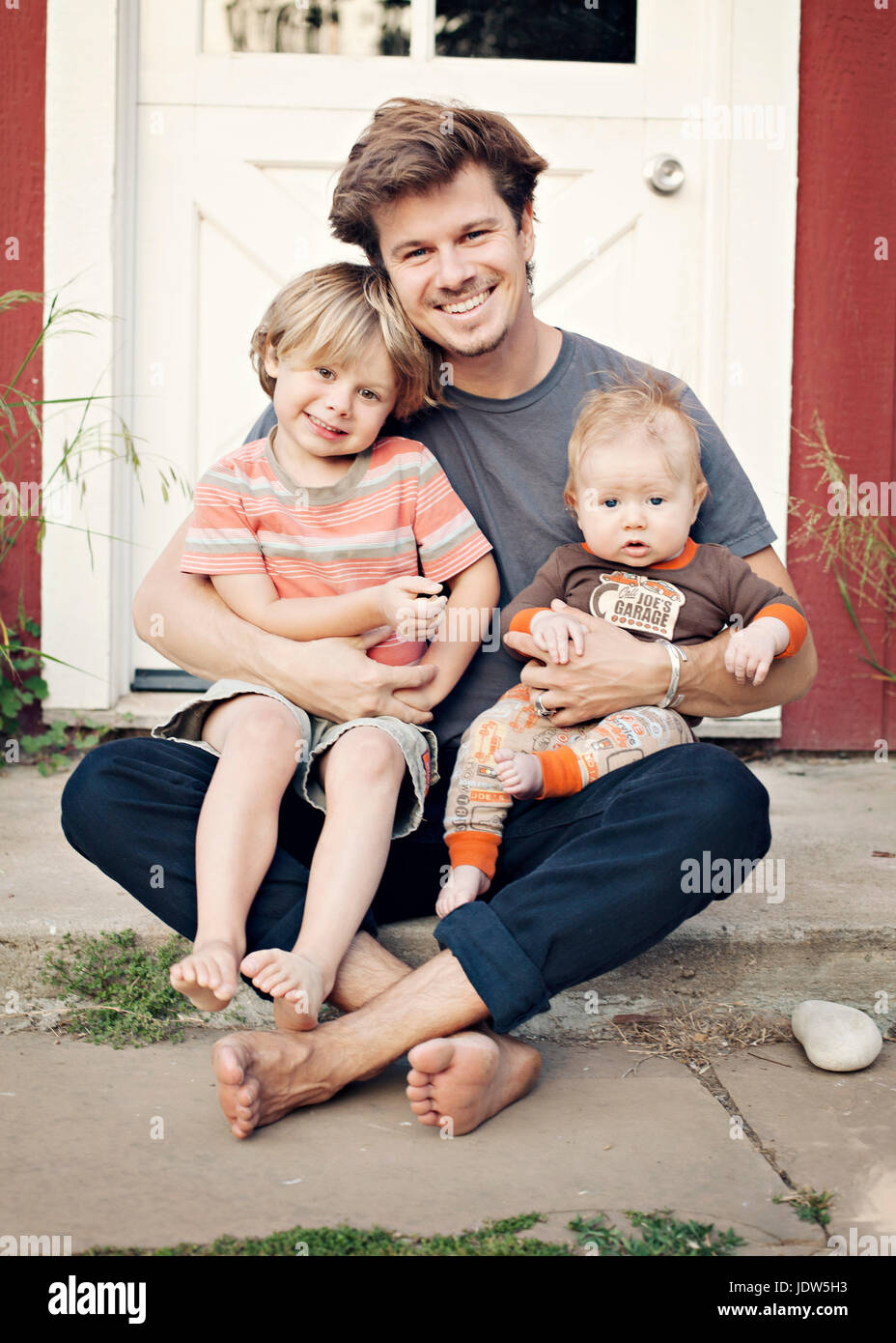 Padre sentado en la puerta con los niños sobre su rodilla Fotografía de  stock - Alamy
