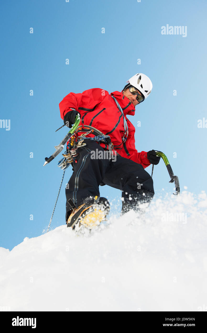 Mitad hombre adulto escalada en nieve, ángulo bajo Foto de stock