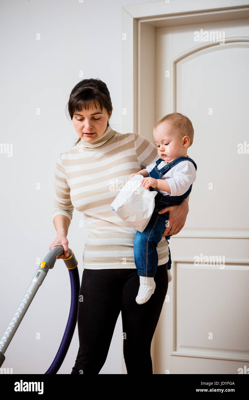 La limpieza de la habitación - Madre con aspiradora sostiene a su bebé en  las manos Fotografía de stock - Alamy