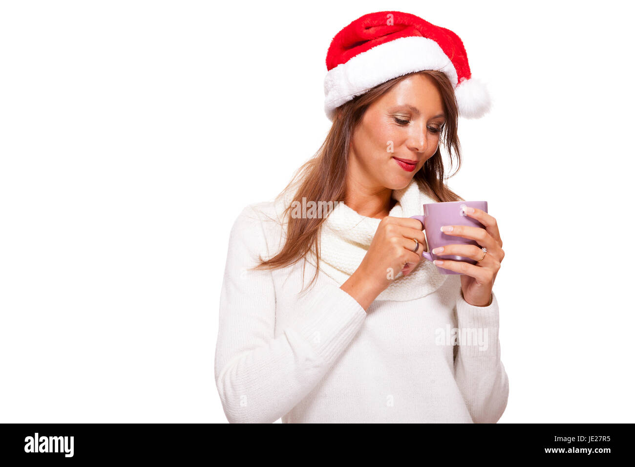 Attraktive junge Frau mit roter Nikolausmütze trinkt einen heißen Becher Kaffee den sie in ihren Händen wiegt um Ihre Hände zu wärmen Isoliert Freisteller Foto de stock