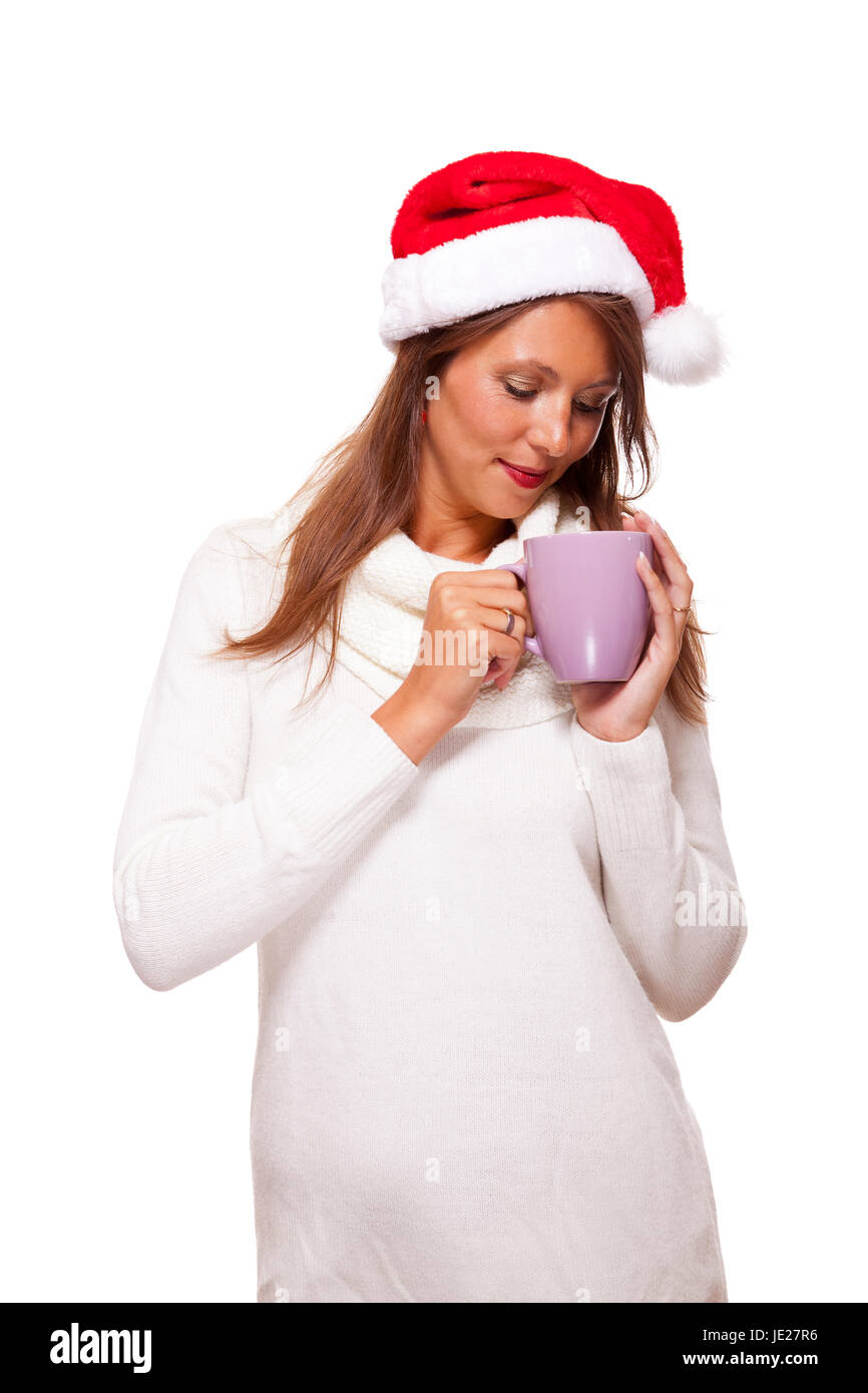 Attraktive junge Frau mit roter Nikolausmütze trinkt einen heißen Becher Kaffee den sie in ihren Händen wiegt um Ihre Hände zu wärmen Isoliert Freisteller Foto de stock