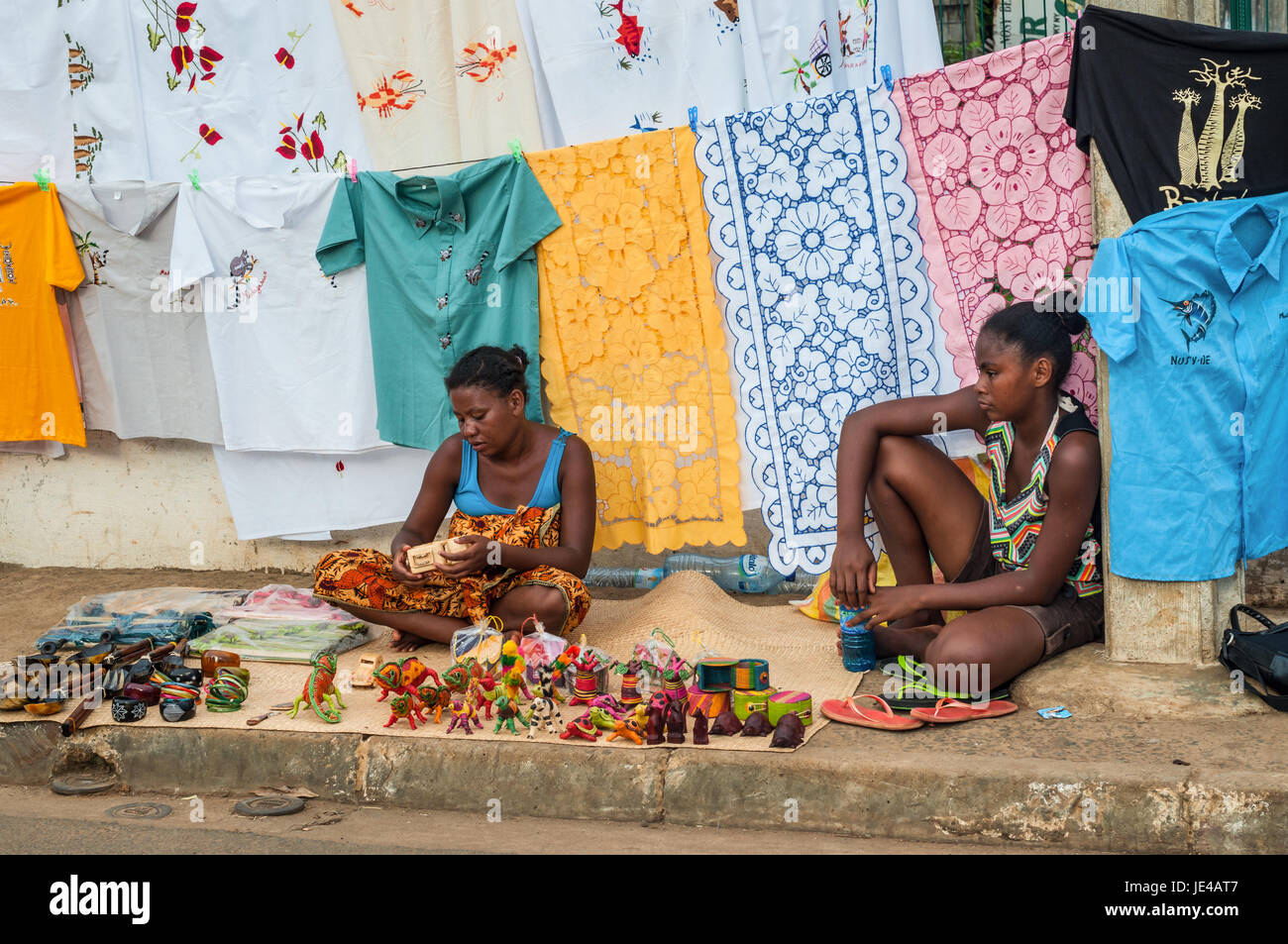 Hell-Ville, Madagascar - Diciembre 19, 2015: Las mujeres indígenas venden coloridas manteles bordados, tejidos y recuerdos en la carretera al Hell-Vill Foto de stock
