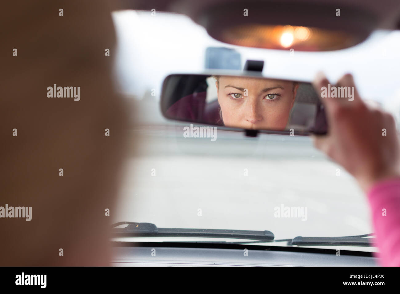 Hermosa señorita mirando hacia atrás a través del espejo retrovisor desde  el asiento delantero de un vehículo durante la marcha atrás Fotografía de  stock - Alamy