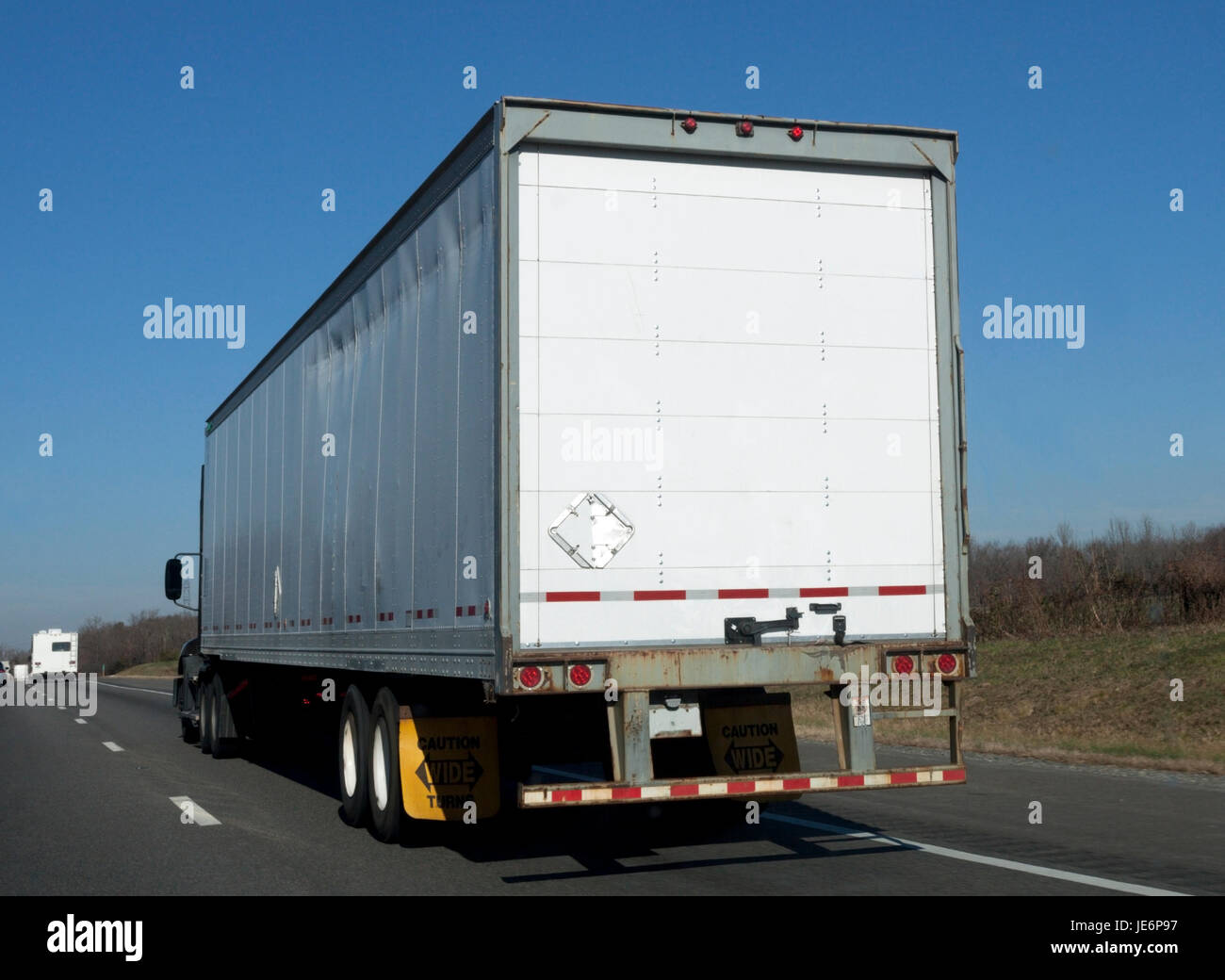 Vista trasera de blanco semi en la autopista bajo un cielo azul. Foto de stock
