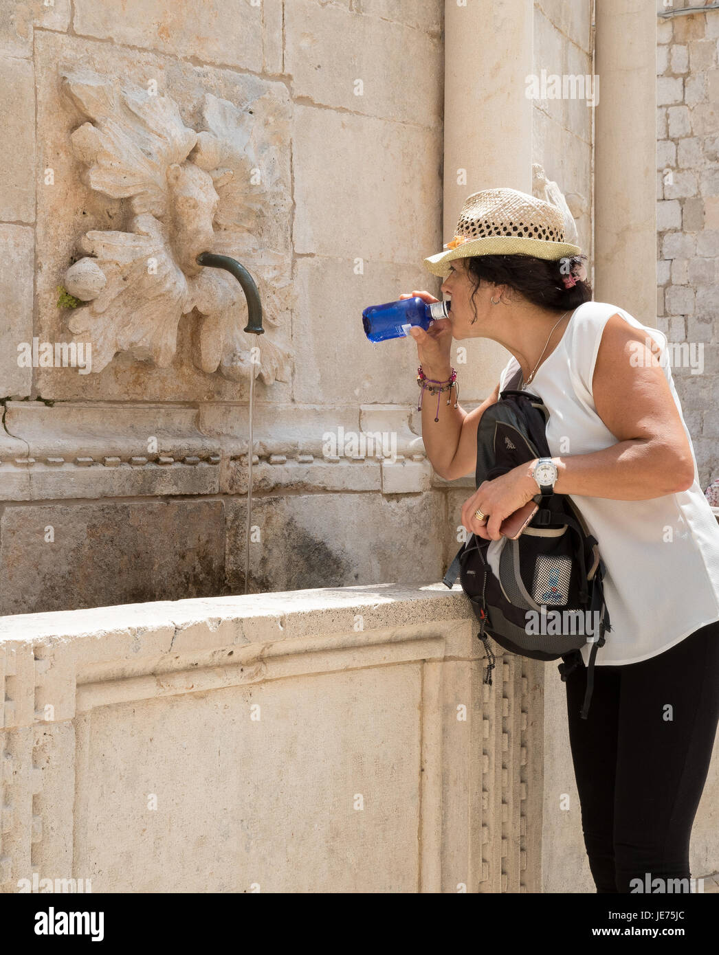 Un turista de beber el agua de la gran fuente de Onofrio más allá de la Puerta Pile en la ciudad vieja de Dubrovnik, en la costa dálmata de Croacia Foto de stock