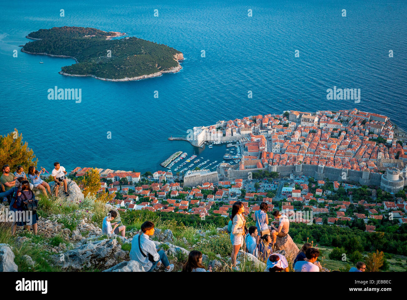 Los turistas ven la puesta de sol sobre Dubrovnik desde la cima del Monte SRD. Foto de stock