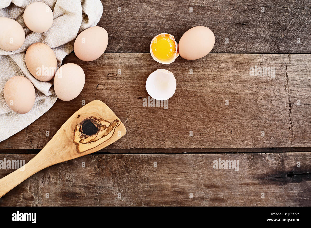 Orgánicos frescos de granja de huevos de pollo marrón Free Range pollos con un viejo olivo espátula antiguas de madera sobre un fondo de madera de estilo rústico. Un huevo agrietado Foto de stock