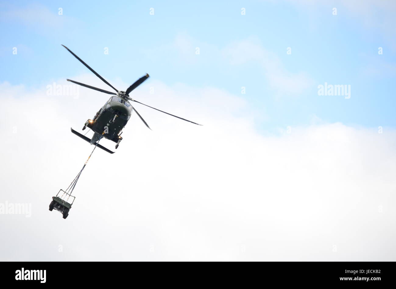 Helicóptero militar verde llevando un Jeep Foto de stock