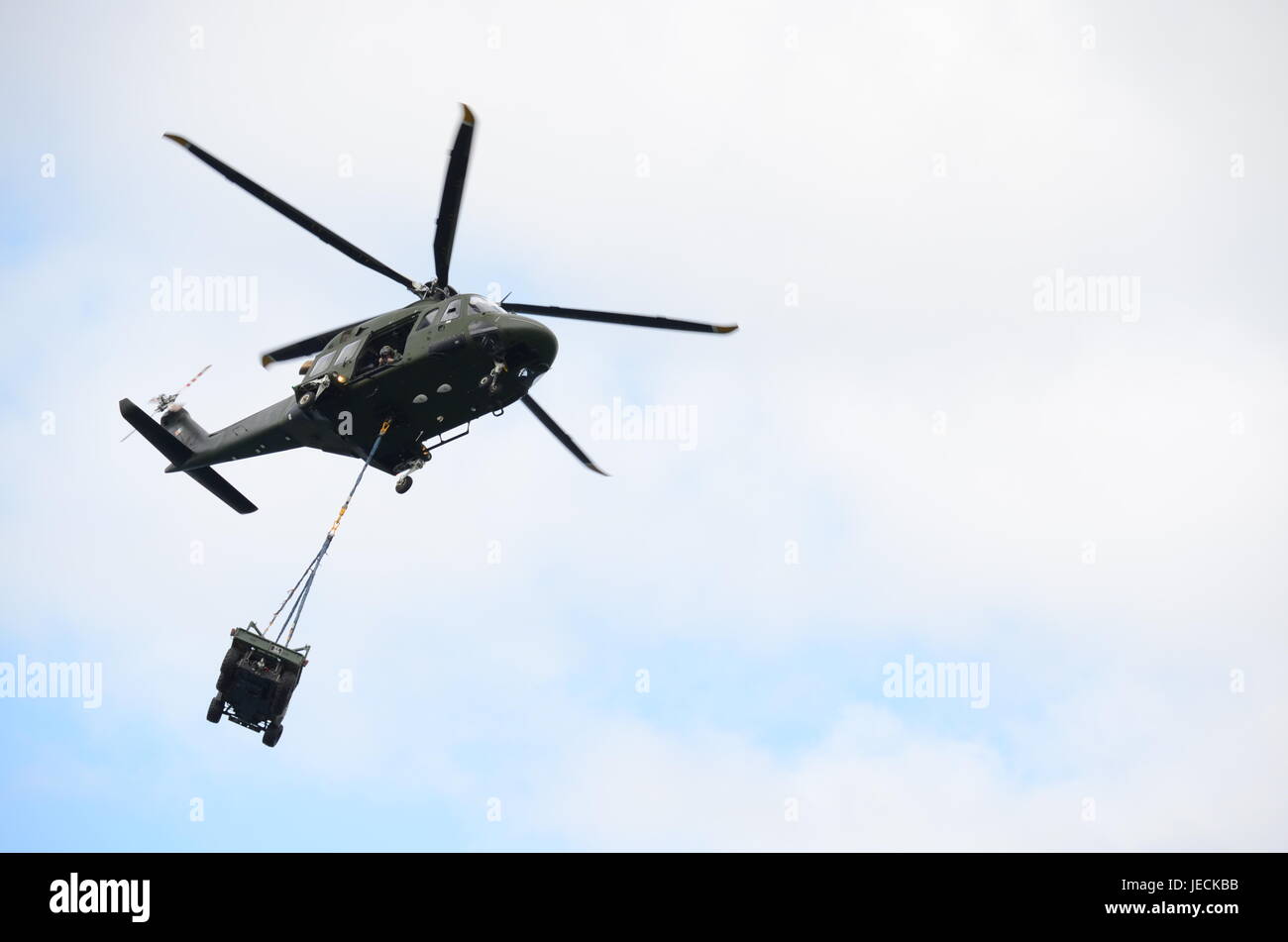 Helicóptero militar verde llevando un Jeep Foto de stock