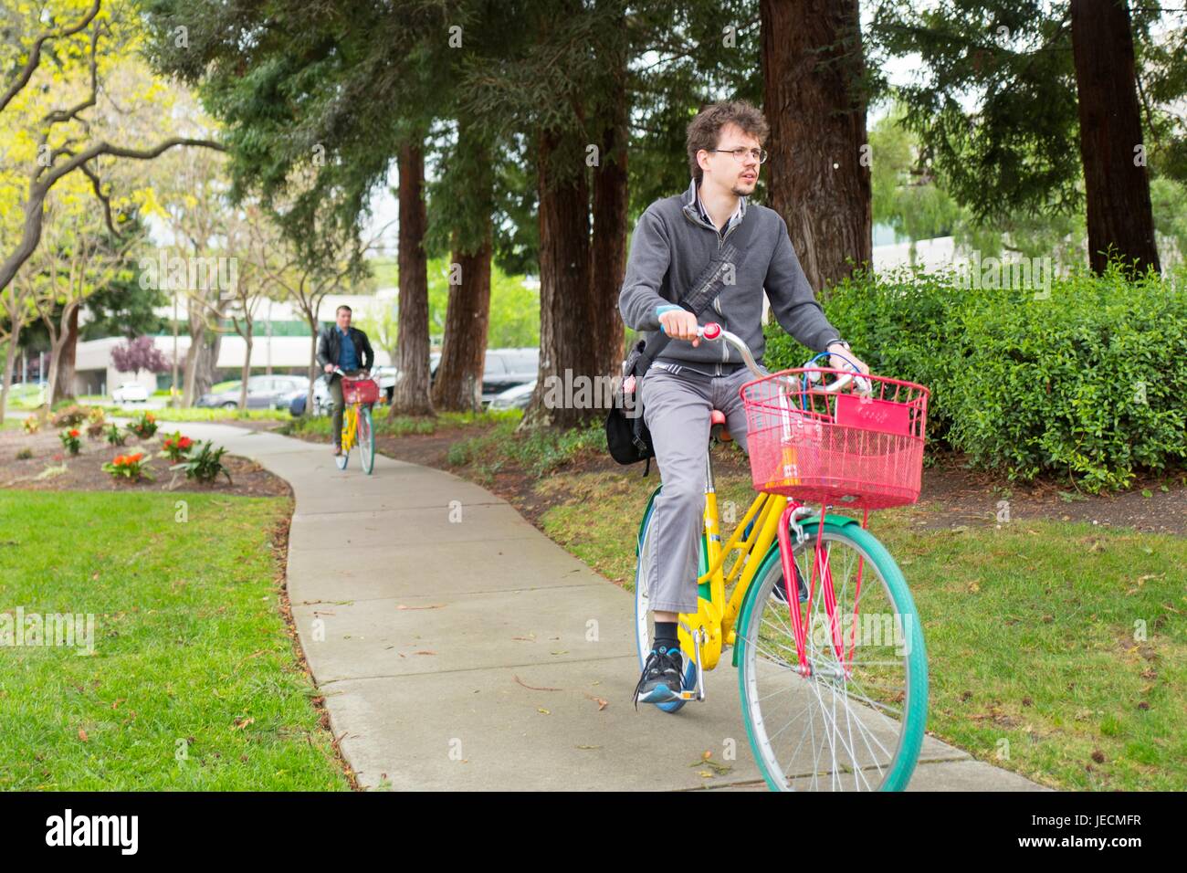 Dos empleados de Google Inc, conocida coloquialmente como Google, Google colorido paseo bicicletas en el Googleplex, la sede de Google Inc en el Silicon Valley, la ciudad de Mountain View, California, 7 de abril de 2017. Foto de stock
