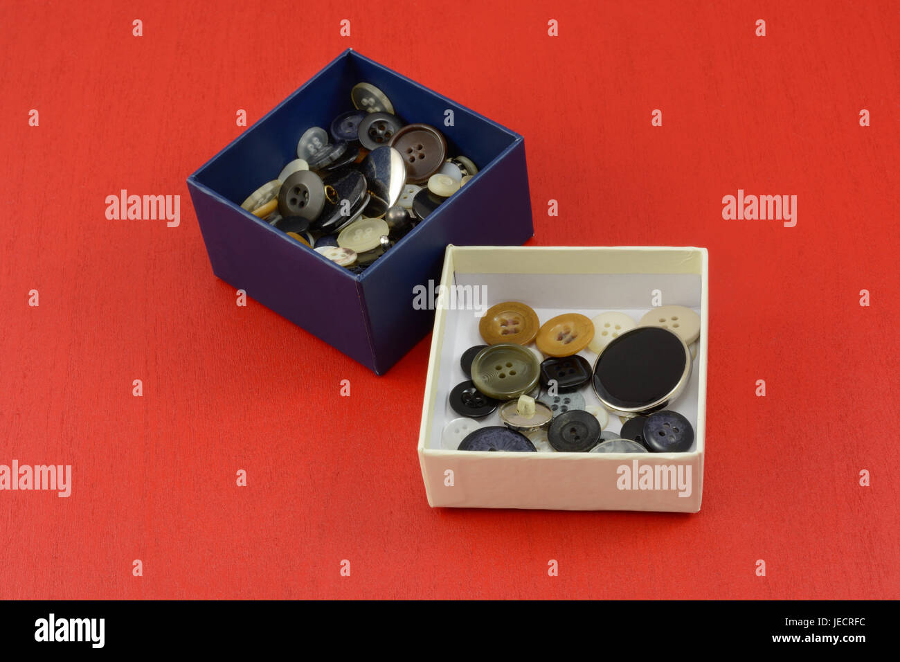 Colección de botones en cuadros blancos y azules sobre fondo de madera roja Foto de stock