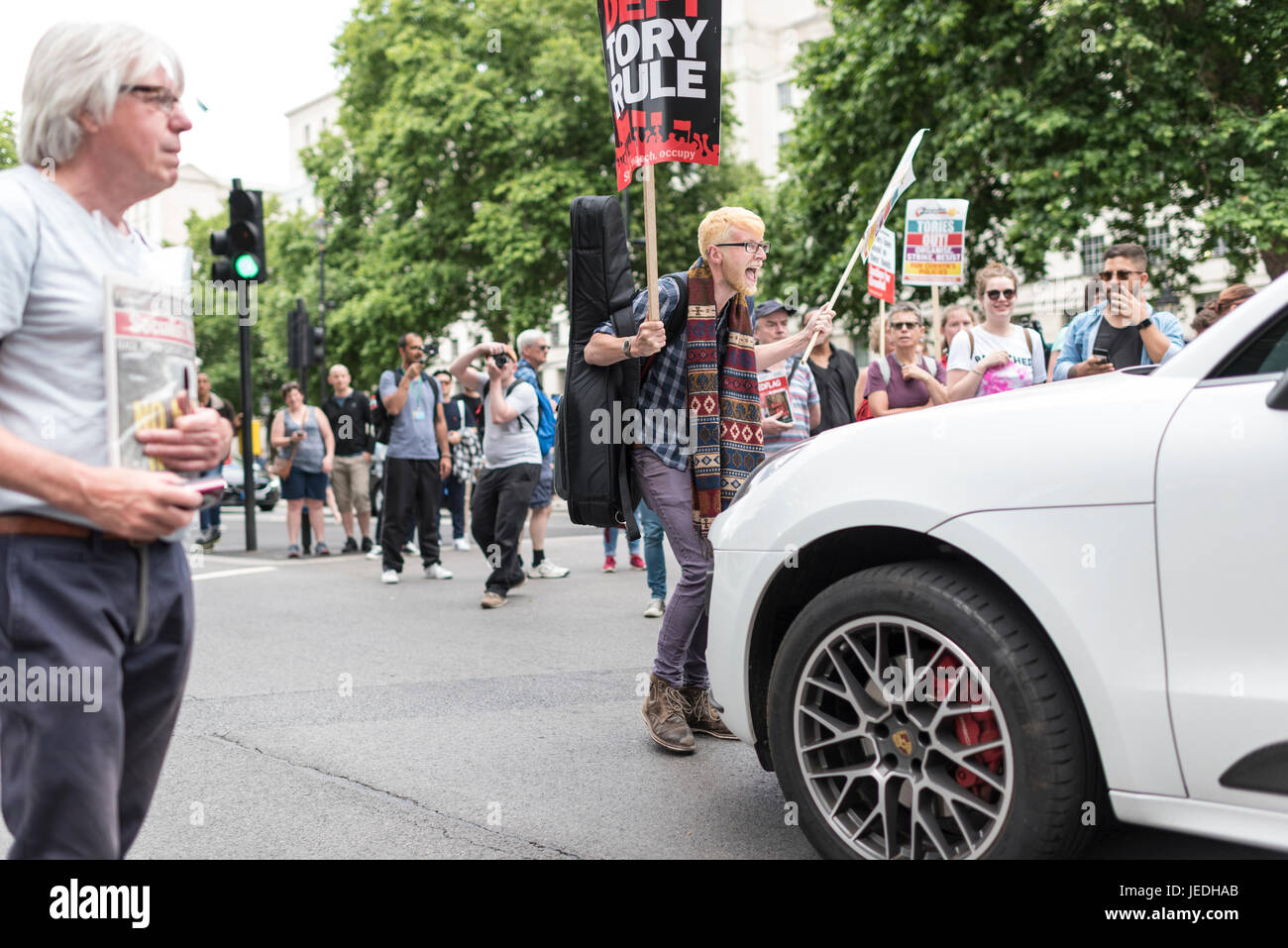 Londres, Reino Unido, 24 de junio de 2017. Los jóvenes protesta frente a Downing Street contra el Gobierno Tory que está tratando de crear una alianza con el DUP. Un manifestante se levanta delante de un coche. Foto de stock