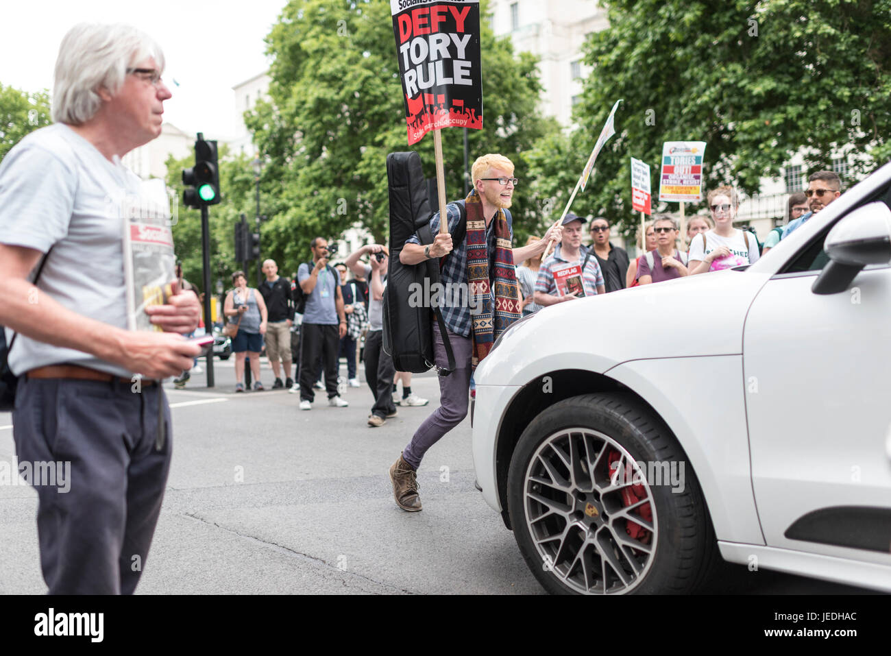 Londres, Reino Unido, 24 de junio de 2017. Los jóvenes protesta frente a Downing Street contra el Gobierno Tory que está tratando de crear una alianza con el DUP. Un manifestante se levanta delante de un coche. Foto de stock