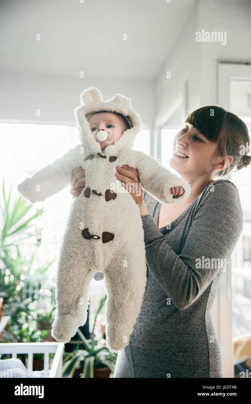 Madre sosteniendo a su bebé en un traje de oso polar Foto de stock