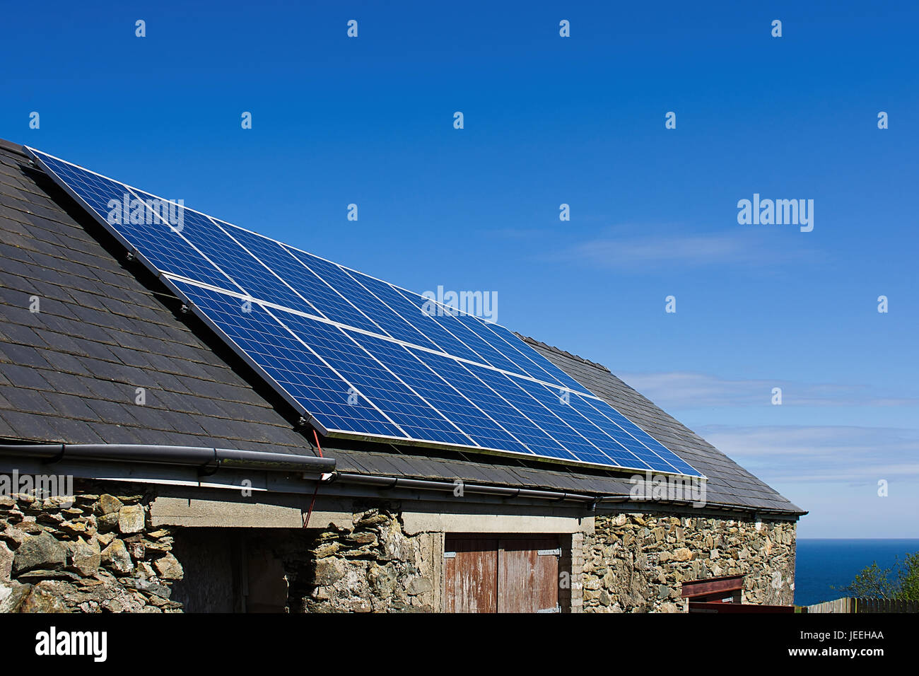 Panel solar en el tejado de pizarra, el cielo azul de fondo, Anglesey, Norte de Gales, Reino Unido.panel solar en el techo de la casa inclinada, Reino Unido.La célula solar. Foto de stock