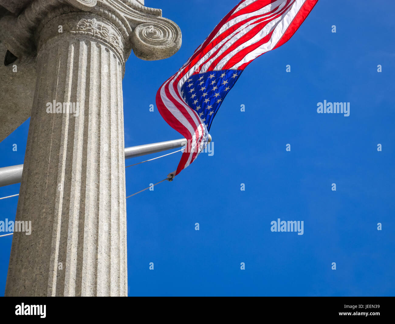 Cerca de bandera americana ondeando contra el cielo azul, el Bunker hill Monument, Charlestown, Boston, Massachusetts, EE.UU. Foto de stock
