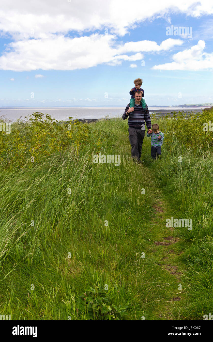 Hombre caminando con sus hijos en Watchet, Somerset, Reino Unido Foto de stock