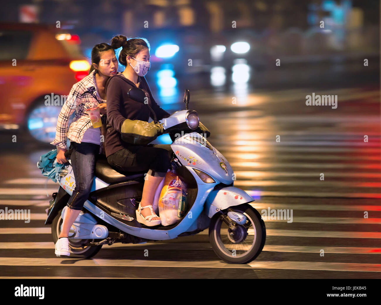 Chicas chinas en bicicleta eléctrica por la noche. Las bicicletas eléctricas  se están volcando en las calles en China. En todo el país hay unos  doscientos millones Fotografía de stock - Alamy