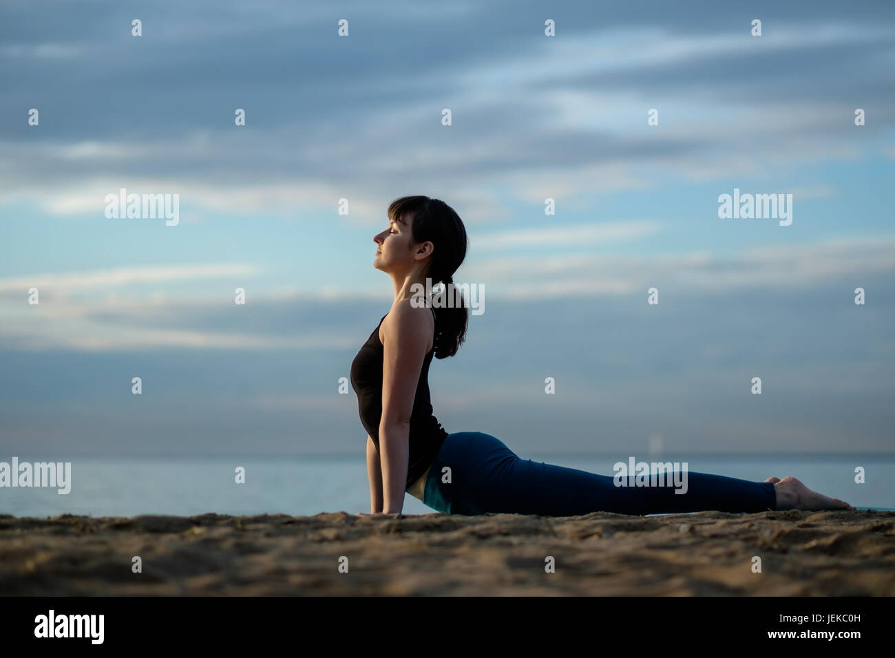 Las asanas de yoga al aire libre en la playa. perro boca arriba plantean Foto de stock