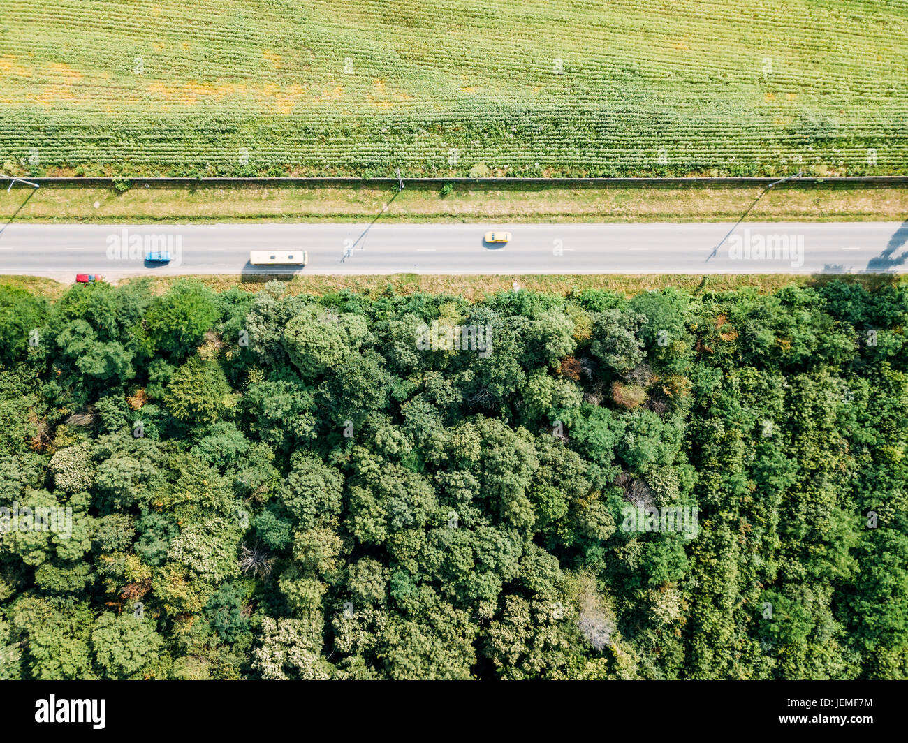 Antena Drone Vista de mover los coches en Country Road con bosques y agricultura campo de cultivo en los lados Foto de stock