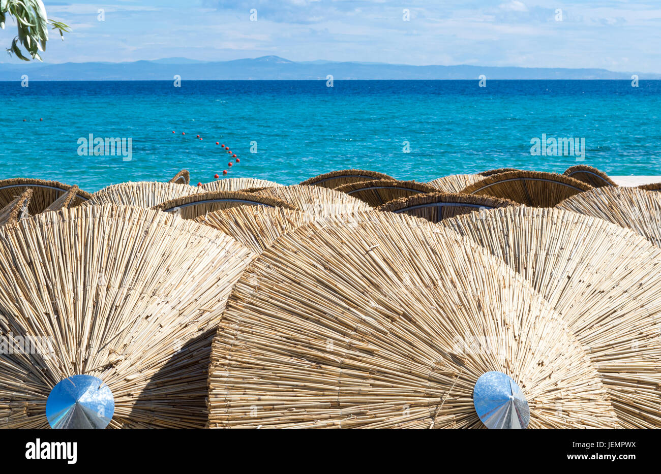 Sombrillas de paja en la playa con vistas al mar Foto de stock