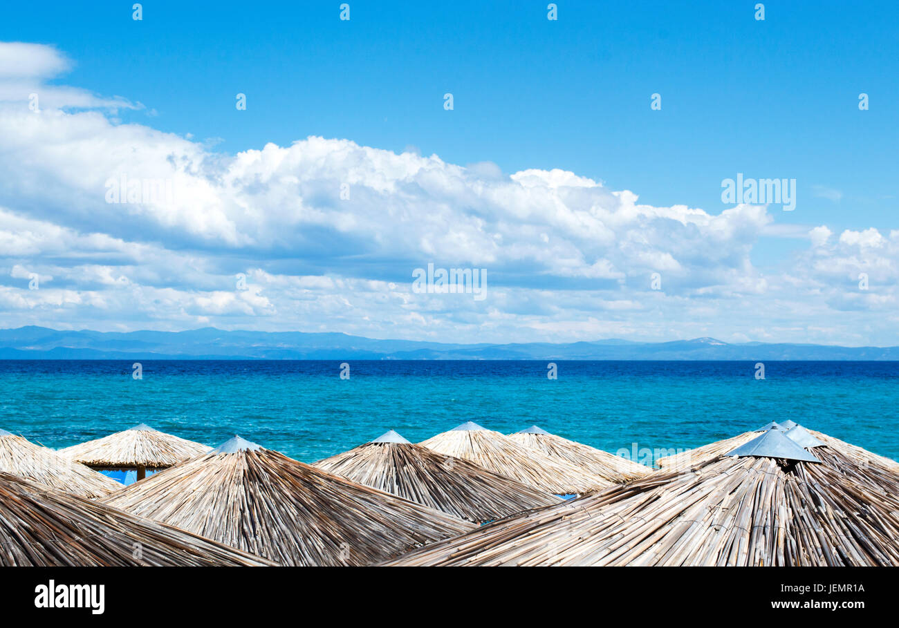 Sombrillas de paja en la playa con vistas al mar Foto de stock