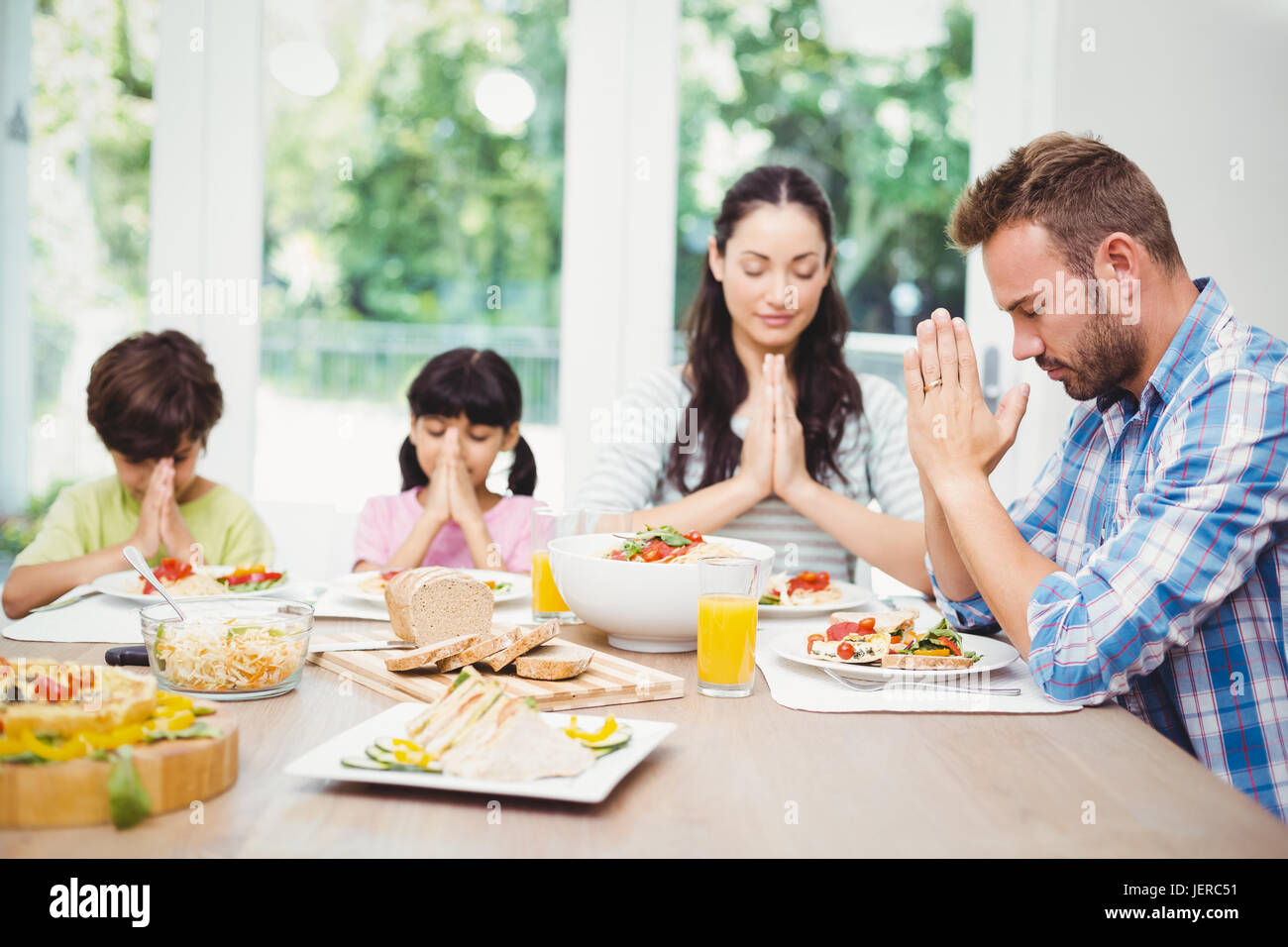 Familia orando mientras está sentado en la mesa de comedor Fotografía de  stock - Alamy