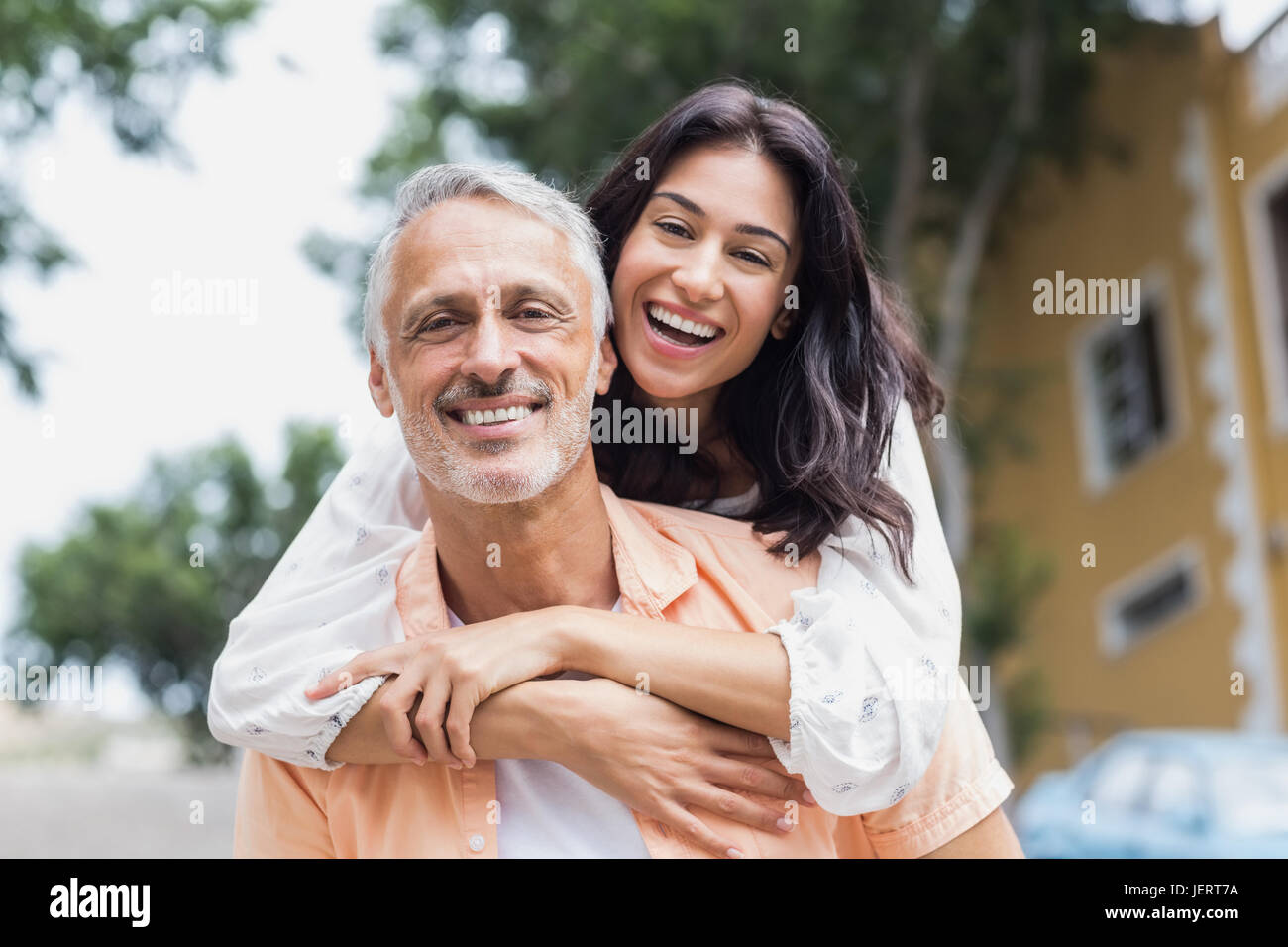 Mujer sonriente abrazando el hombre detrás de Foto de stock