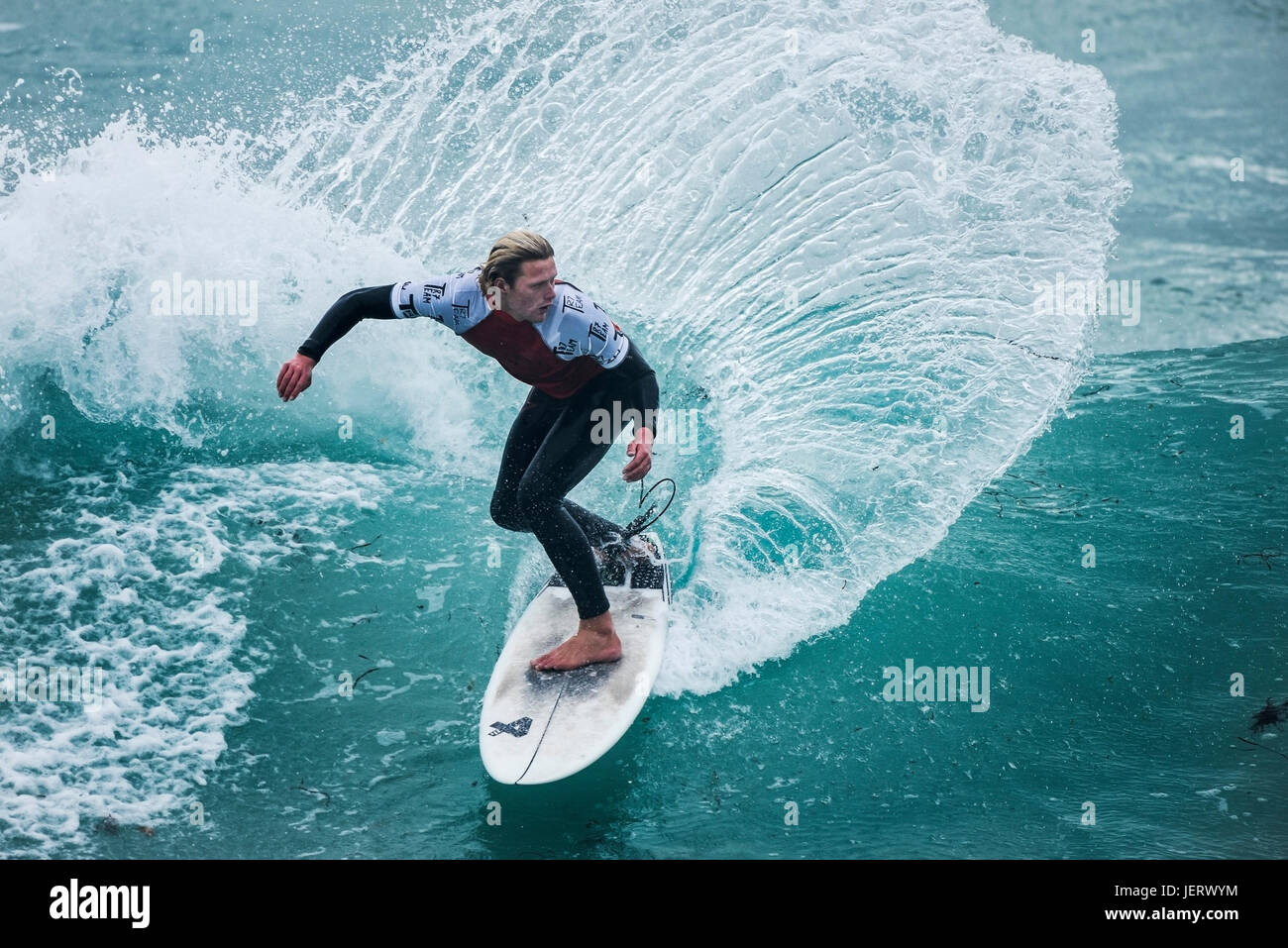 Surf en el Reino Unido. Surf espectacular acción como un surfista monta una ola en una competencia en la playa Fistral en Newquay, Cornwall Foto de stock