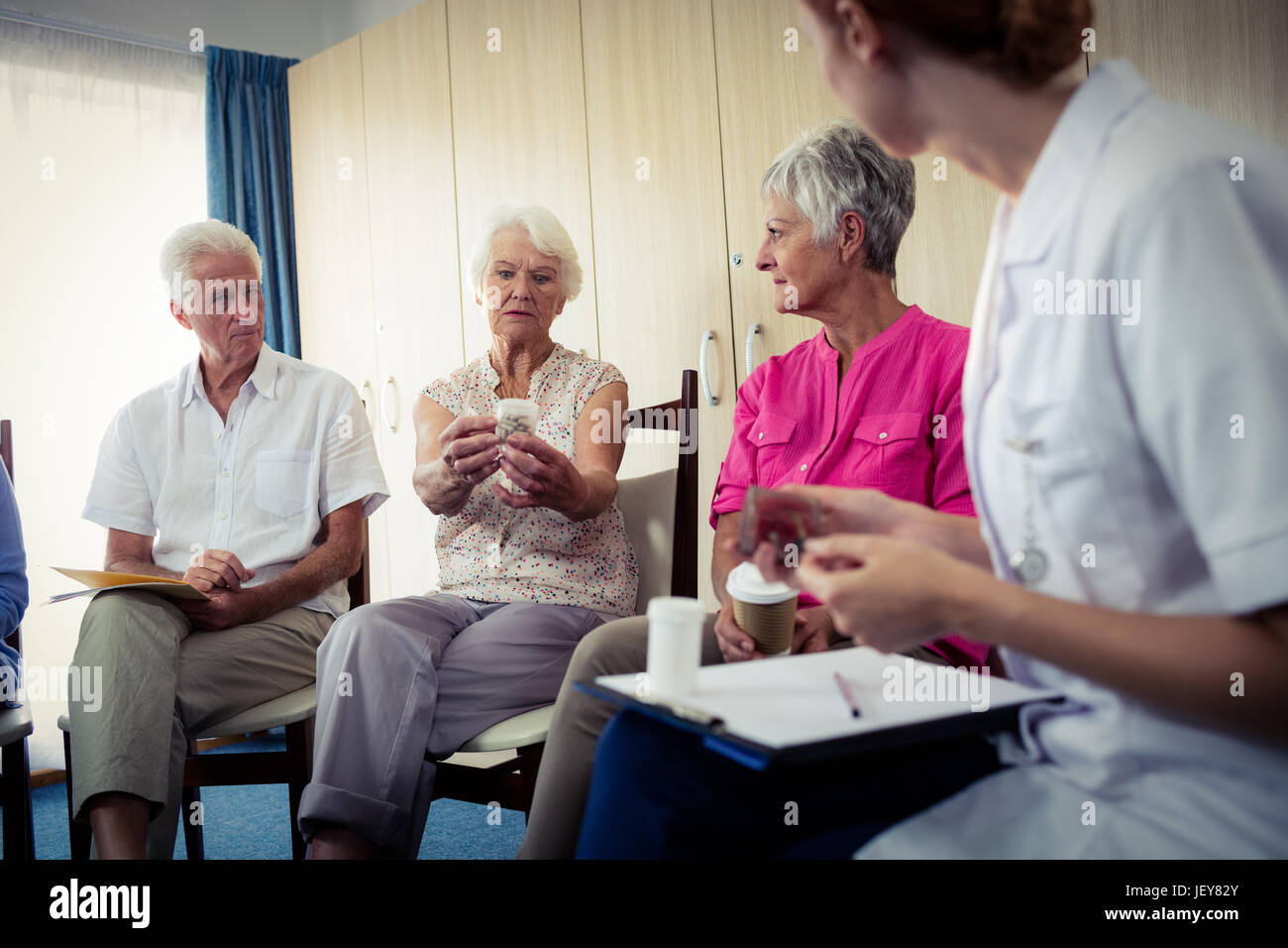 Los ancianos de hablar con la enfermera acerca de medicación Foto de stock