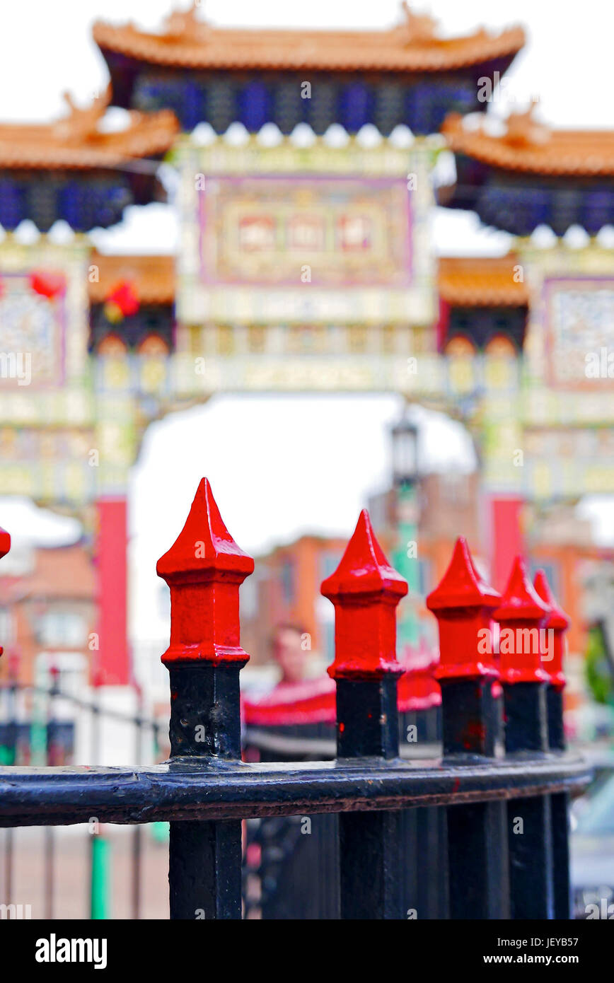 Barandillas de hierro pintadas en negro y rojo frente a un arco chino desenfocado en Chinatown, Liverpool, Reino Unido Foto de stock