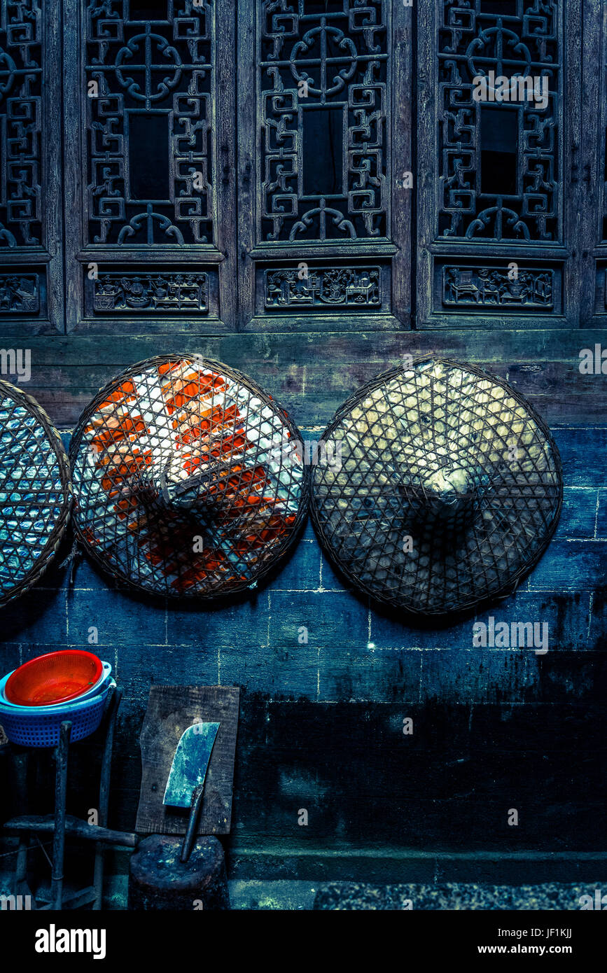 Tres sombreros de paja chino colgado en la pared y gran cuchillo de carnicero debajo, Antigua Villa Chengkan, Huangshan, en la provincia de Anhui, China Foto de stock