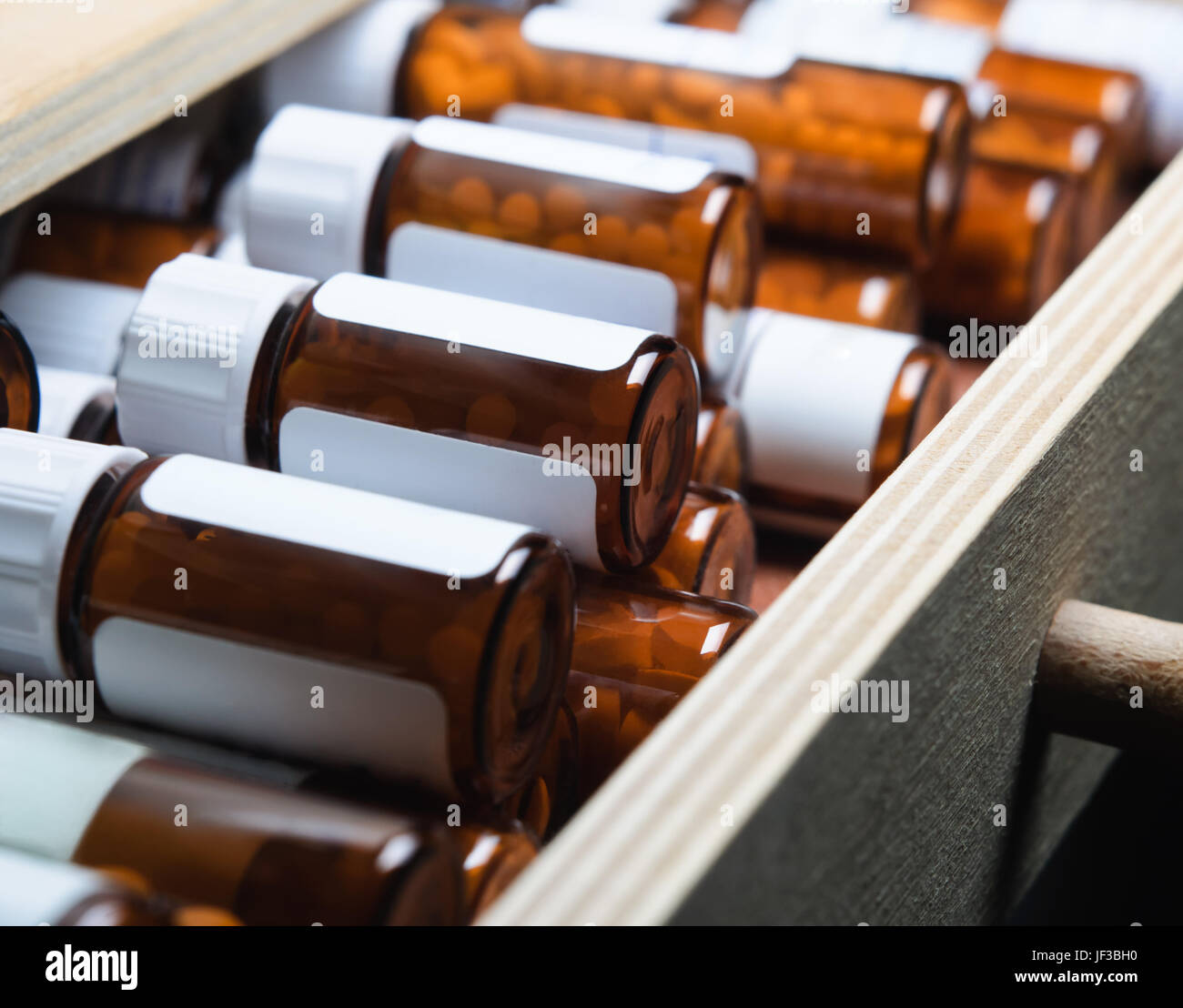 Un cajón abierto, lleno de muchas botellas de vidrio ámbar con remedios homeopáticos. Orientación horizontal (horizontal). Foto de stock