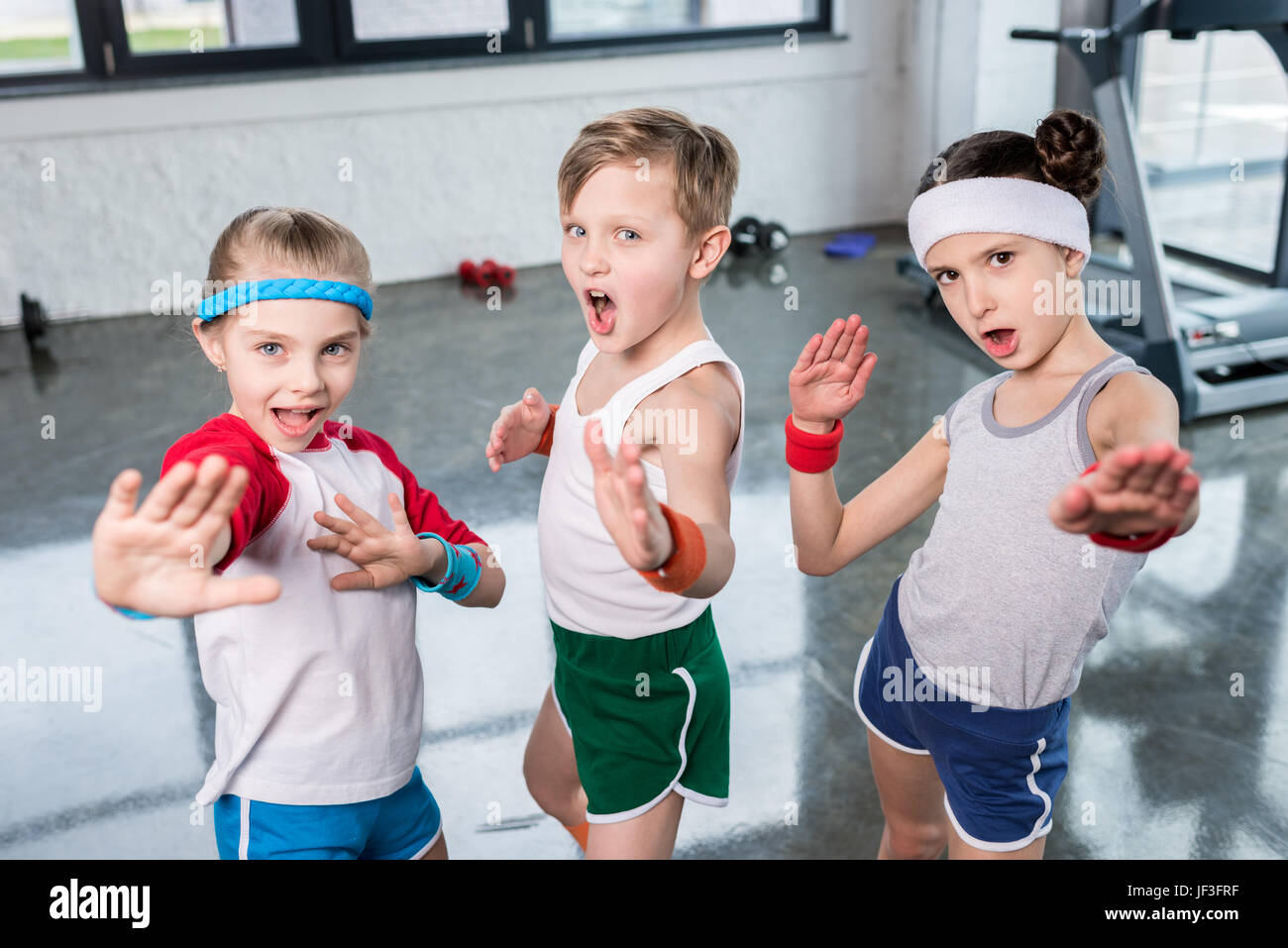 de pequeños en ropa deportiva el ejercicio y posando en cámara en el gimnasio, los niños deporte escolar concepto Fotografía de stock - Alamy