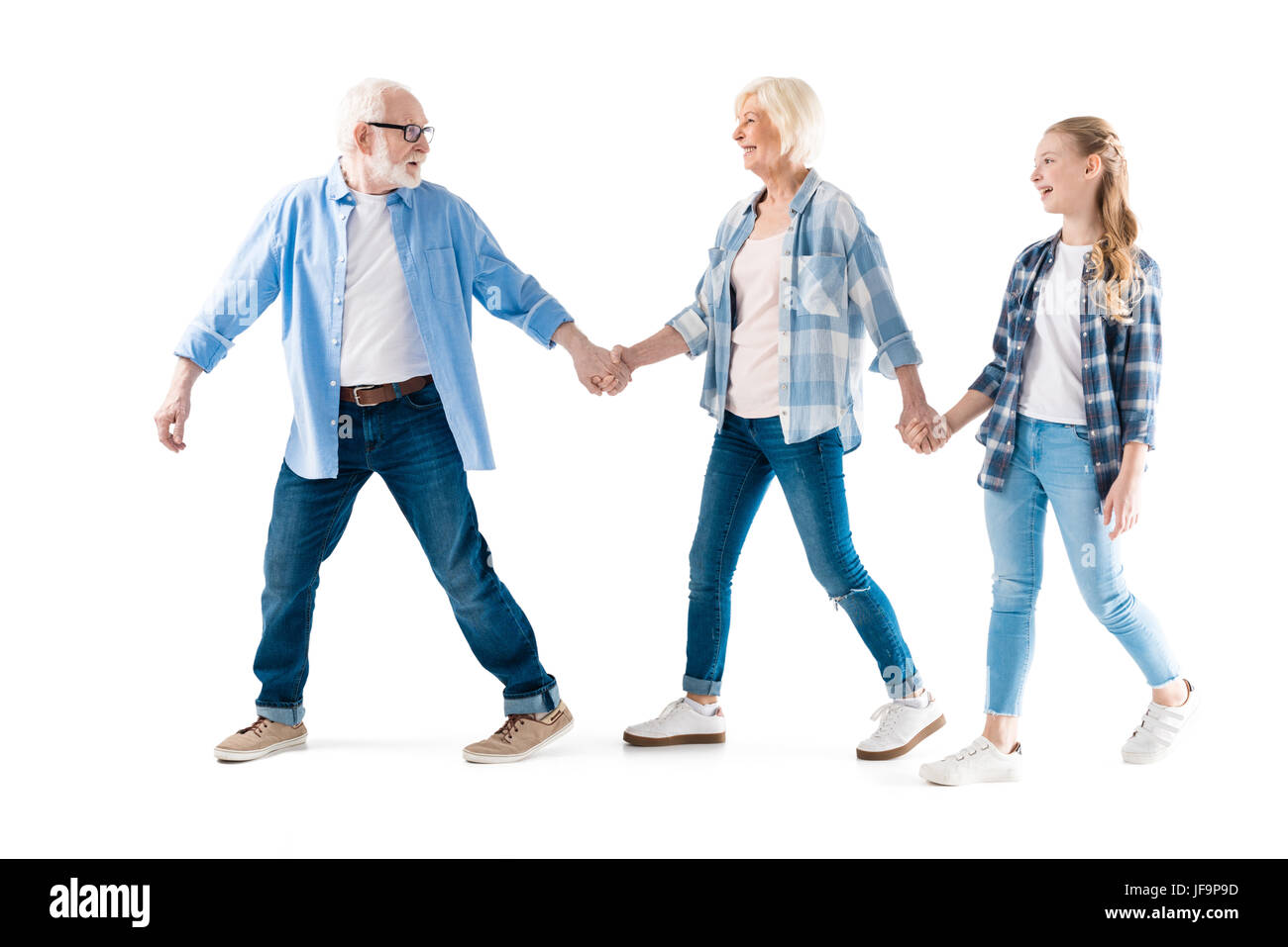 Feliz abuelo, abuela y nieta caminando y tomados de la mano juntos aislado en blanco Foto de stock
