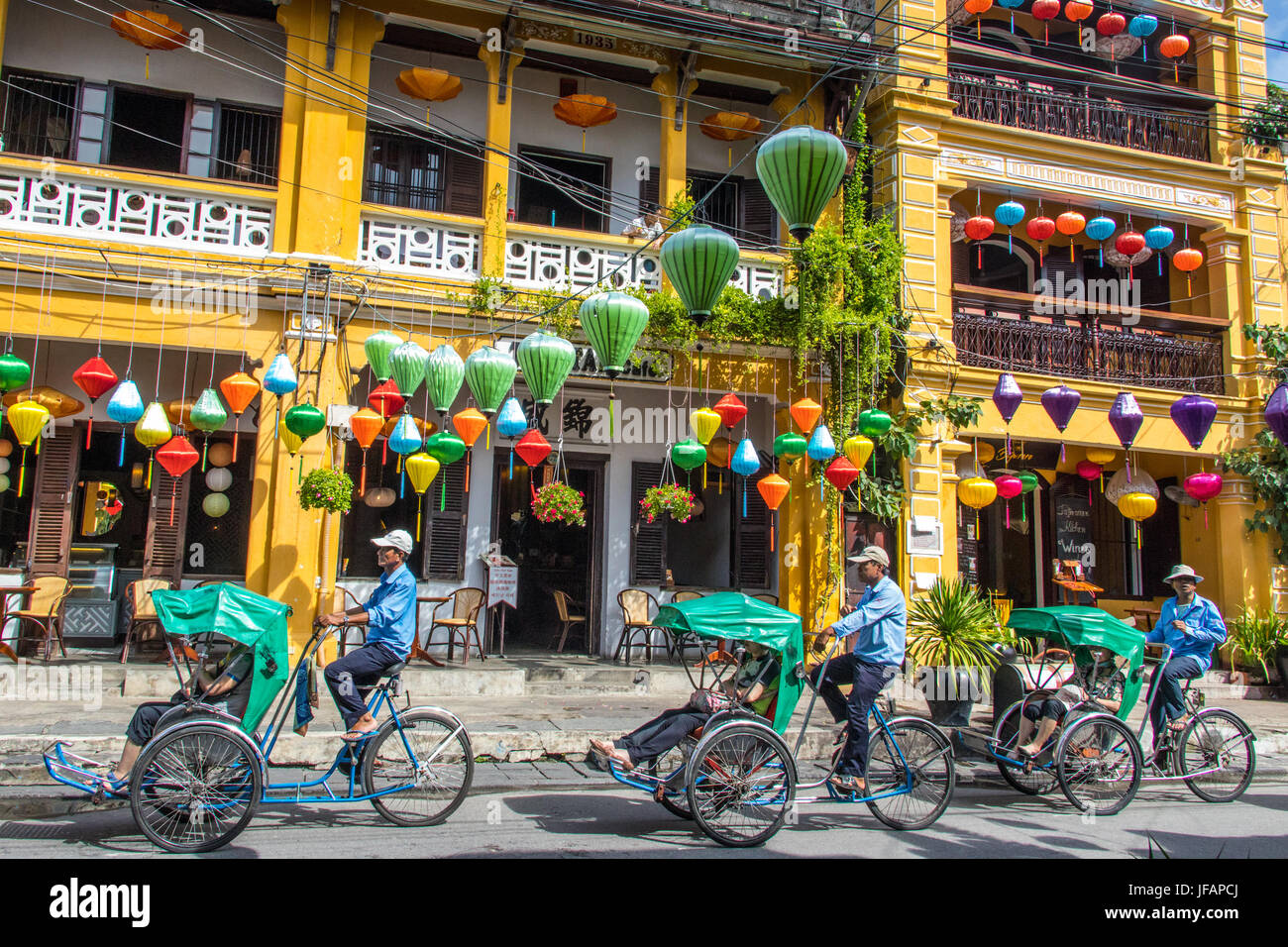 Los turistas en un cyclo tour, coloridos faroles en Hoi An, Vietnam Foto de stock