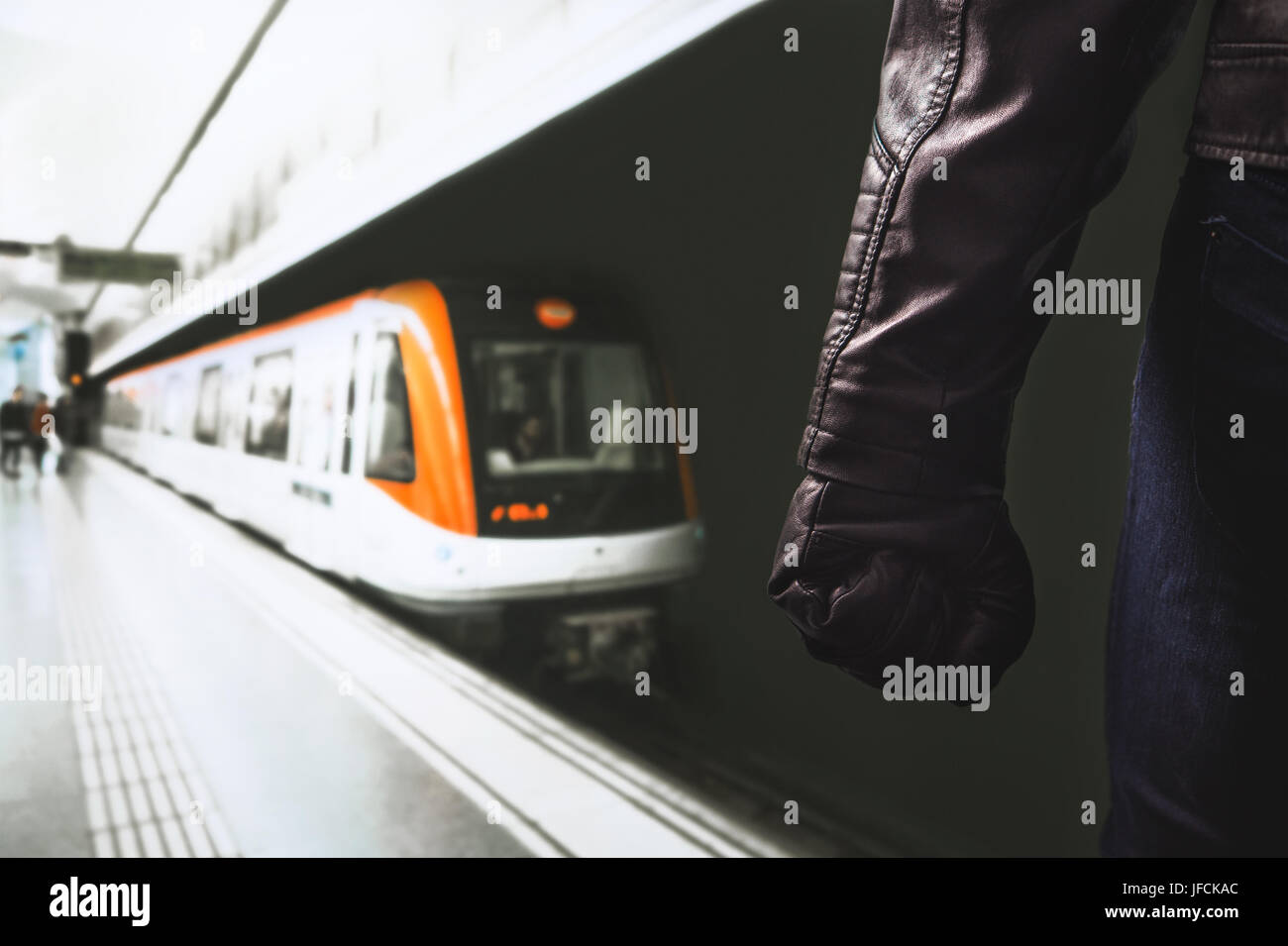 La violencia en el transporte público. Amenaza peligrosa hombre de pie en la plataforma de trenes subterráneos. Puño y brazo con guante de cuero negro. Foto de stock