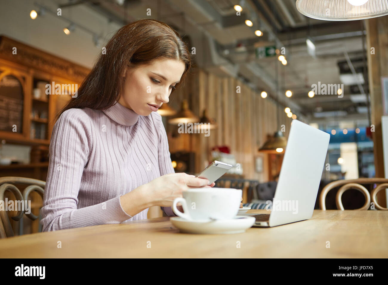 Hermosa morenita con laptop en la cafetería. Concepto de trabajo de Blogger Foto de stock