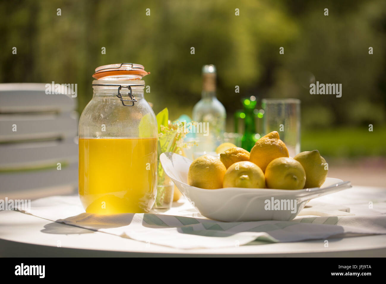 Limoncello casero y limones en plato de frutas Foto de stock
