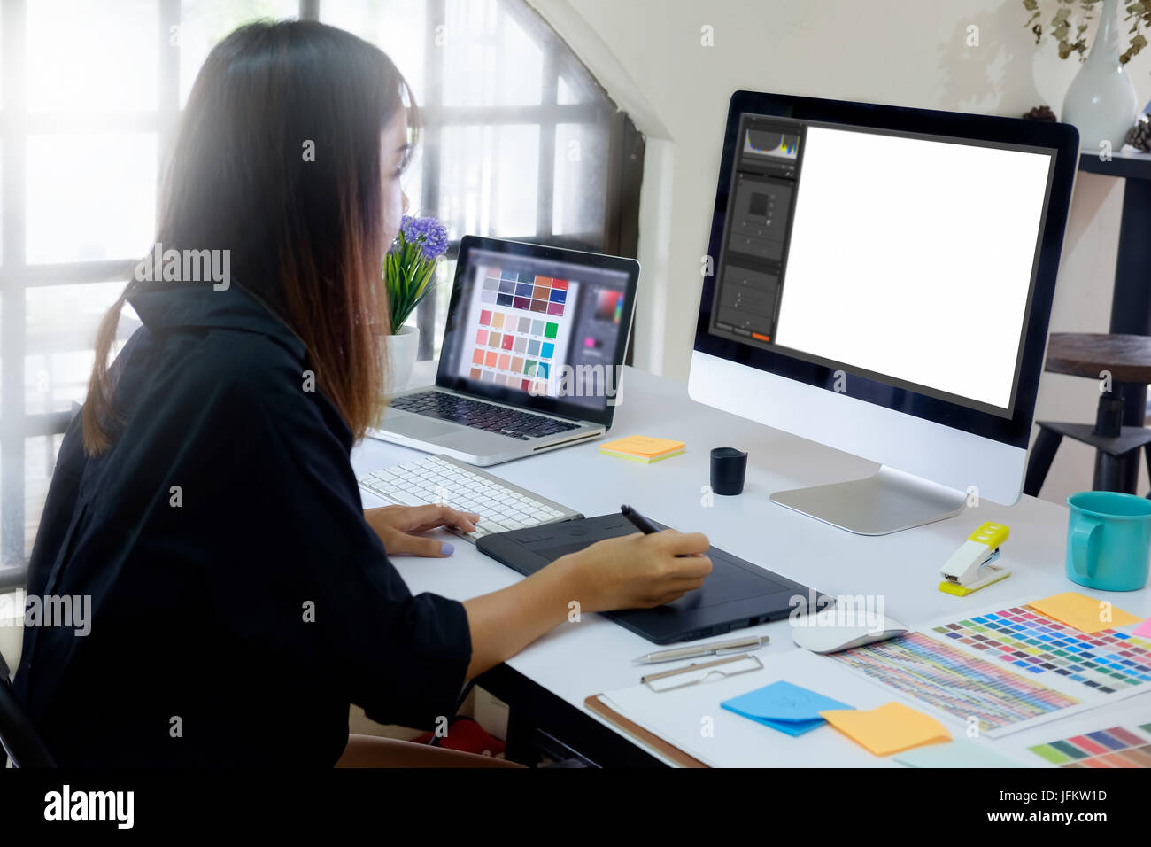 Joven fotógrafo y diseñador gráfico en el trabajo en la oficina. Monitor de pantalla en blanco para la visualización gráfica de montaje. Foto de stock